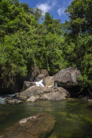 Mann genießt schönen Wasserfall mit Felsen und grünem Regenwald