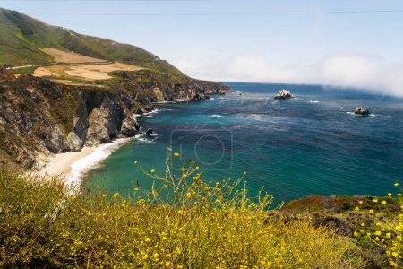 Coastal cliffs and turquoise waters along Big Sur under a misty sky