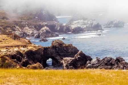 Rocky coastline with sea arches in a misty Big Sur landscape