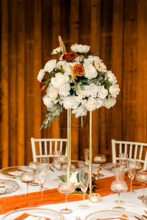 Hochzeitstisch mit weißen und orangefarbenen Blumen
