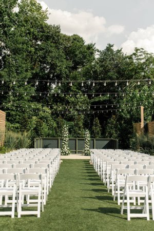 Téléchargez les photos : Wedding ceremony setup with white chairs and lights - en image libre de droit