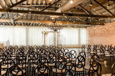 Indoor wedding ceremony with chairs, floral arch, and chandelier