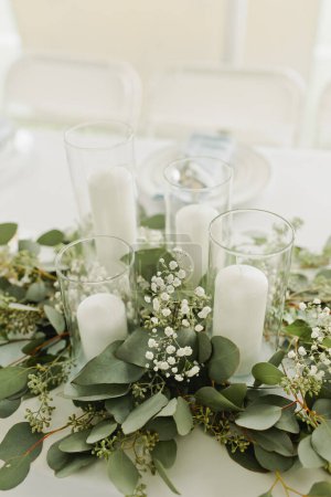 Elegante mesa de bodas con vegetación y altas velas blancas