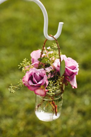 Arrangement de fleurs violettes et roses dans un bocal en verre suspendu