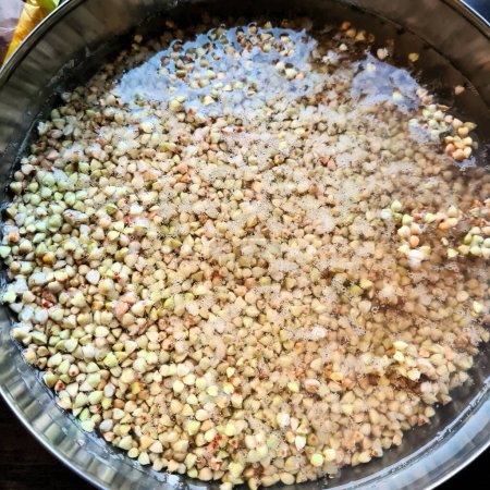 evocative image of buckwheat grains immersed in water in a metal container