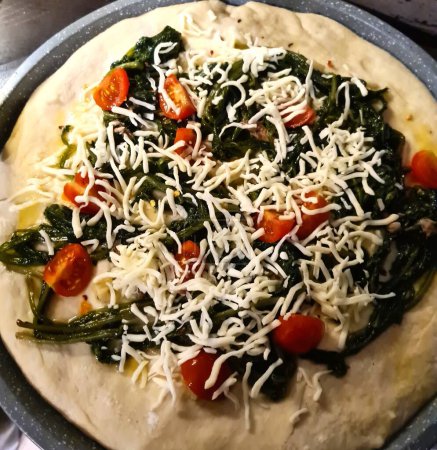 eindrucksvolle Nahaufnahme einer tomatenfreien weißen Pizza mit Brokkoli, geschnittenen Kirschtomaten und Mozzarella zum Backen