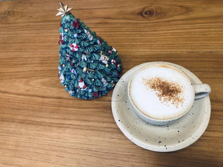 Téléchargez les photos : Tasse de café cappuccino chaud avec arbre de Noël vert décoratif en céramique sur une table en bois brun - en image libre de droit