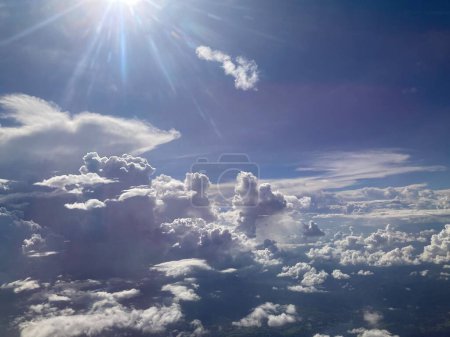 vista de nubes blancas y esponjosas llenó el cielo y rayos radiales se extendieron desde el sol brillante mientras volaba en un avión