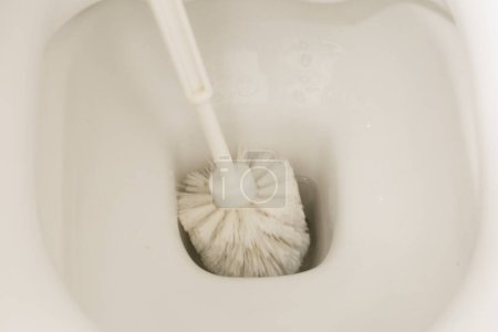Foto de Una nueva toma de la no tan glamorosa tarea de limpiar el inodoro, esta foto muestra la precisión y eficiencia de un cepillo de inodoro, ya que elimina la suciedad y las manchas. - Imagen libre de derechos