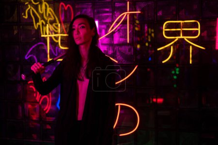 Photo for Portrait of an asian man holding a bat in a neon studio - Royalty Free Image