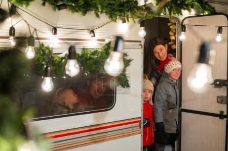 Téléchargez les photos : Heureuse grande famille célèbre Noël dans la nature. Les parents avec trois fils voyagent dans une maison mobile - en image libre de droit