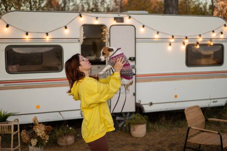Photo pour Femme caucasienne aux cheveux roux étreint un chien et vit dans un camping-car. Voyage en roulotte - image libre de droit
