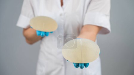 Doktor plastischer Chirurg demonstriert verschiedene Brustimplantate