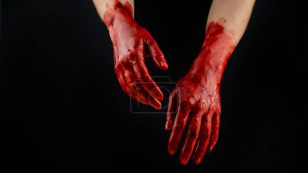 Téléchargez les photos : Femmes mains dans le sang sur un fond noir - en image libre de droit