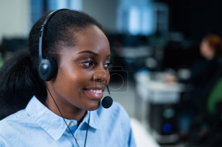 Mujer joven africana hablando con un cliente con auriculares. Empleada del call center