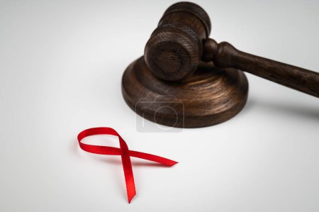 Photo for Judicial gavel and red ribbon on a white background. Symbol of the fight against AIDS - Royalty Free Image