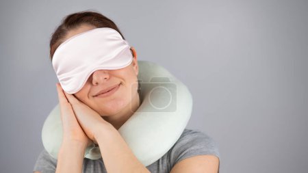 Lächelnde kaukasische Frau mit Reisekissen und Schlafmaske auf weißem Hintergrund