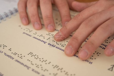 Sehbehinderter Mann liest ein Braillebuch