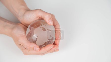 Téléchargez les photos : Globe de cristal dans les mains féminines sur un fond blanc - en image libre de droit