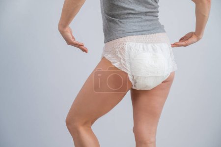 Rear view of a woman pointing at adult diapers. Incontinence problem