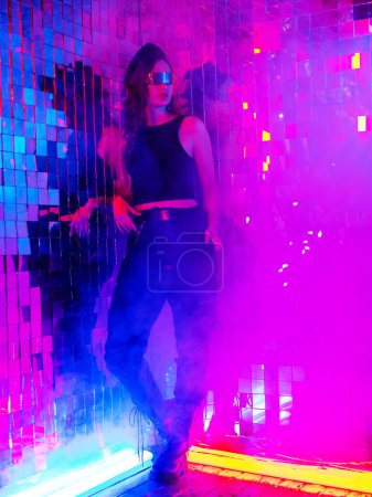 Photo for Portrait of a caucasian woman in sunglasses in neon light against a mirror wall - Royalty Free Image