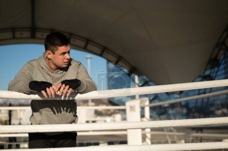 Téléchargez les photos : Boxeur masculin caucasien reposant dans le ring à l'extérieur - en image libre de droit