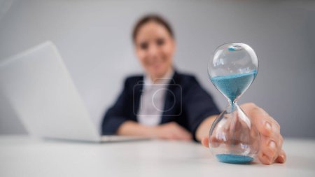 Photo for Business woman flipping an hourglass at her desk - Royalty Free Image