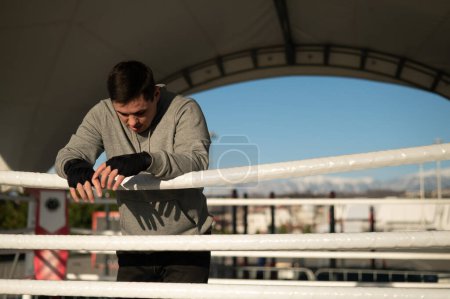 Téléchargez les photos : Boxeur masculin caucasien reposant dans le ring à l'extérieur - en image libre de droit