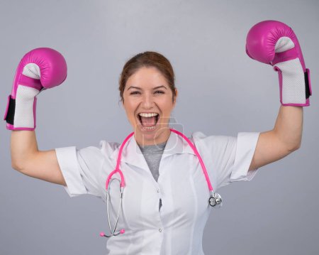 Photo for A female doctor raised her hands in pink boxing gloves as a sign of victory over the disease - Royalty Free Image