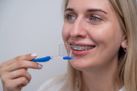 Téléchargez les photos : Femme caucasienne nettoyer ses dents avec des bretelles à l'aide d'une brosse - en image libre de droit