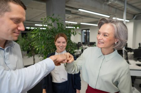 Téléchargez les photos : Homme caucasien cogner ses poings avec des collègues comme un signe de succès - en image libre de droit