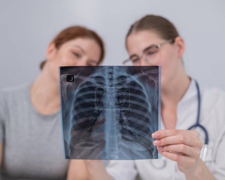 Photo for The doctor consults a caucasian woman and comments on the x-ray of the lungs - Royalty Free Image