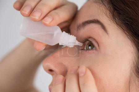 Photo for Caucasian woman dripping moisturizing drops into her eyes - Royalty Free Image