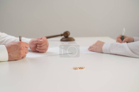 Ehepartner unterschreiben Scheidungspapiere im Studio auf weißem Hintergrund