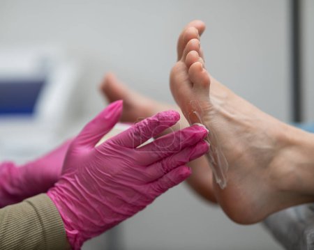 Foto de El maestro aplica la crema y masajea los pies de una clienta - Imagen libre de derechos
