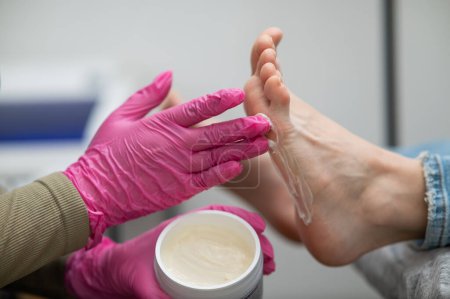 Foto de El maestro aplica la crema y masajea los pies de una clienta - Imagen libre de derechos