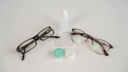 Photo for Two pairs of glasses lenses and contact drops in the eyes on a white table - Royalty Free Image