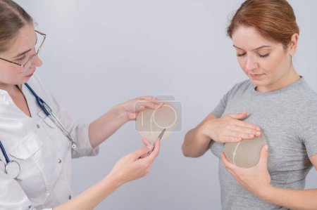 Femme blanche essayant des implants mammaires. Un chirurgien plasticien aide un patient à choisir