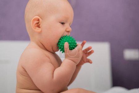 Foto de Niño masticando una bola de masaje verde - Imagen libre de derechos