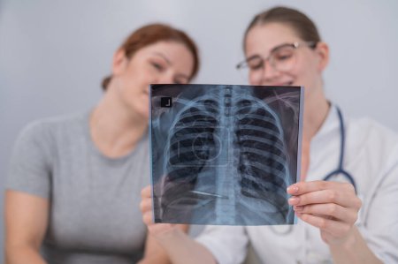 Photo for The doctor consults a caucasian woman and comments on the x-ray of the lungs - Royalty Free Image