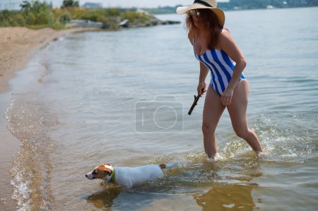 Foto de Mujer caminando por la orilla del río con su perro Jack Russell Terrier - Imagen libre de derechos