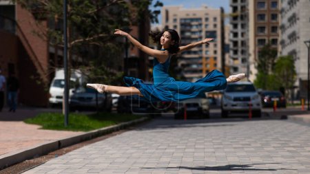 Foto de Hermosa bailarina asiática bailando al aire libre. Paisaje urbano. Gran jete - Imagen libre de derechos