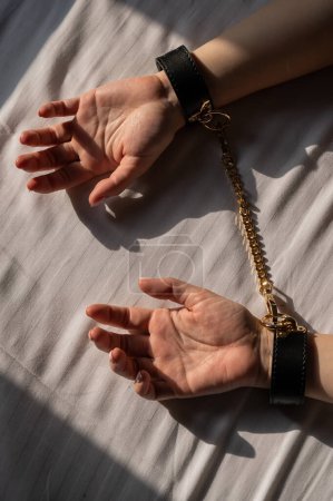 Close-up of womans hands in leather handcuffs. Sex toy