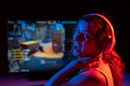 Mujer caucásica pide un poco más de tiempo para jugar a la computadora en luz de neón en la oscuridad