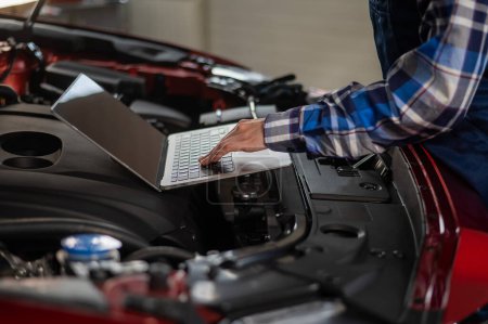 Automechanikerin macht Motordiagnose mit Laptop