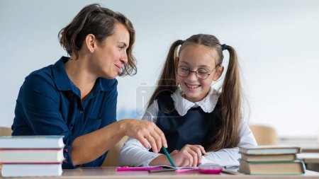 The teacher explains the task to the schoolgirl in the classroom