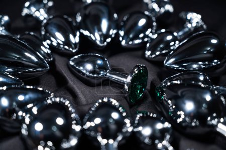 Foto de Muchos tapones anales de metal en una sábana de seda negra - Imagen libre de derechos