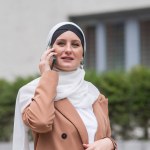 Young woman in hijab talking on smartphone outdoors
