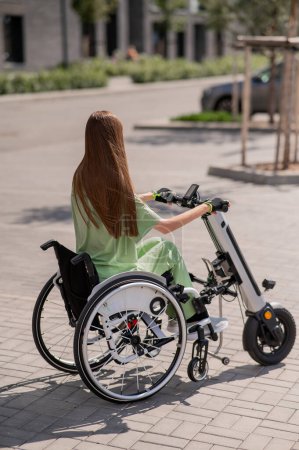 Foto de Una mujer en silla de ruedas con un dispositivo de asistencia para el control manual. Handbike eléctrico - Imagen libre de derechos
