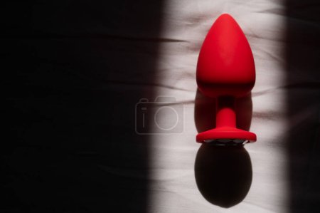 Foto de Plug anal de silicona roja sobre una sábana blanca - Imagen libre de derechos